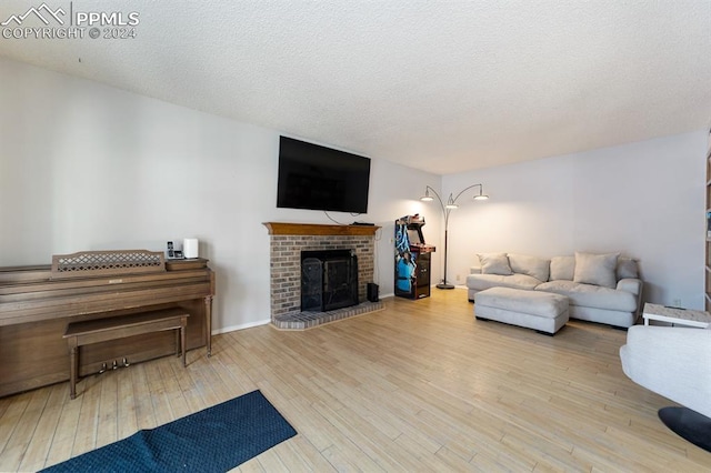 living room with a fireplace, light hardwood / wood-style floors, and a textured ceiling