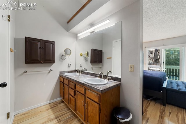 bathroom featuring a textured ceiling, vanity, wood-type flooring, and vaulted ceiling