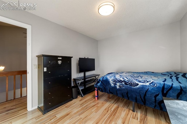 bedroom featuring light hardwood / wood-style floors and a textured ceiling