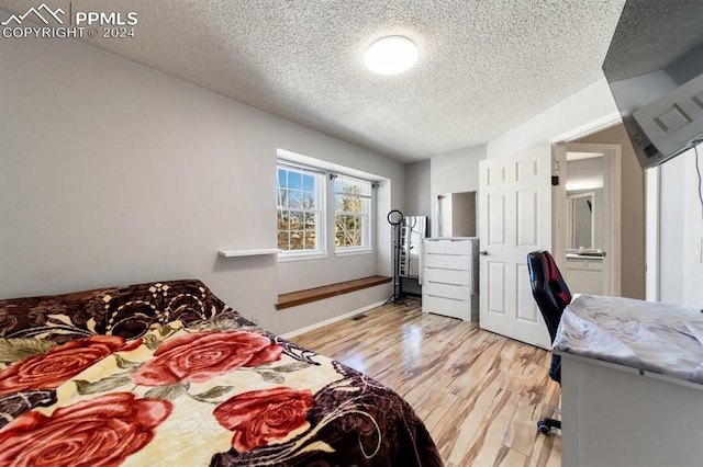 bedroom featuring a textured ceiling and light hardwood / wood-style flooring