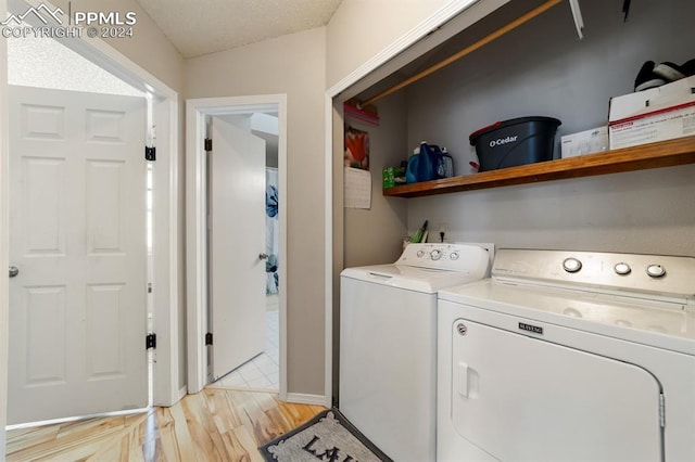 washroom featuring a textured ceiling, light wood-type flooring, and separate washer and dryer