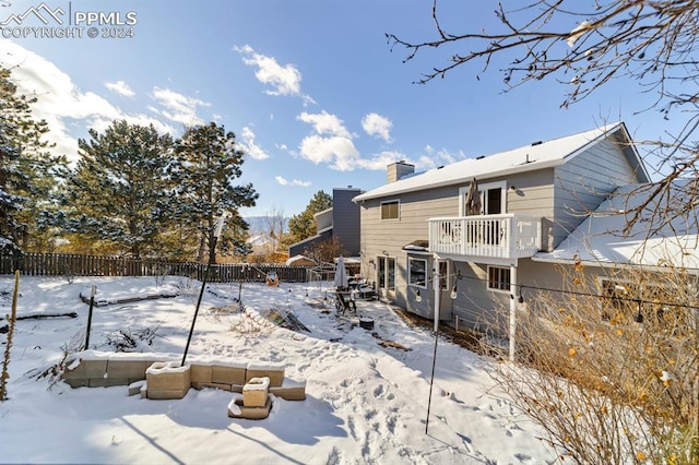 snow covered rear of property featuring a balcony