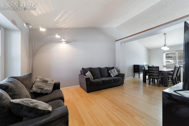 living room featuring a textured ceiling, hardwood / wood-style flooring, and lofted ceiling