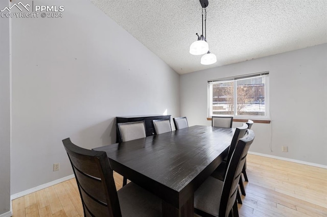 dining room with light hardwood / wood-style floors, lofted ceiling, and a textured ceiling