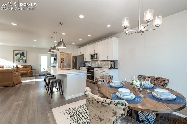 dining space featuring light hardwood / wood-style floors, sink, and an inviting chandelier