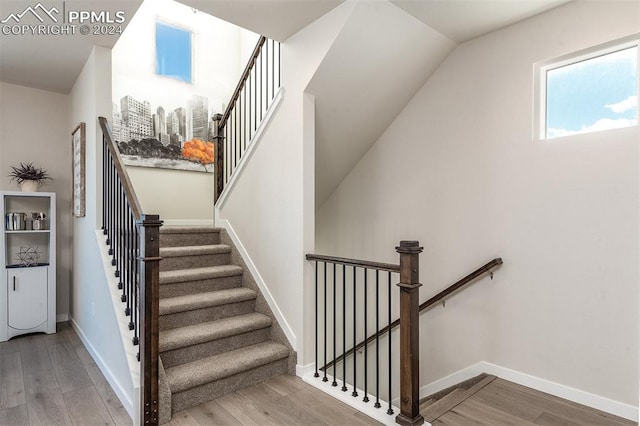 staircase with vaulted ceiling and hardwood / wood-style flooring