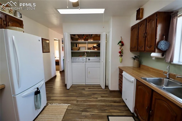 kitchen with a skylight, white appliances, sink, washer and dryer, and dark hardwood / wood-style floors