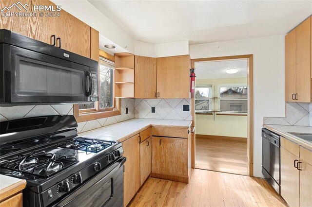928 Alexander Rd, Colorado Springs, CO 80909 - kitchen featuring decorative backsplash, plenty of natural light, black appliances, and light hardwood / wood-style floors