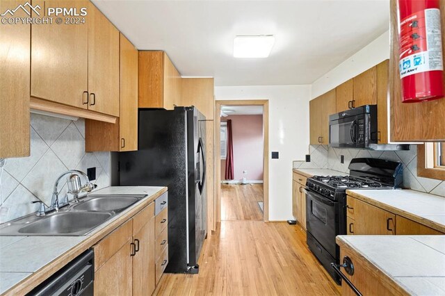 928 Alexander Rd, Colorado Springs, CO 80909 - kitchen with decorative backsplash, sink, black appliances, light hardwood / wood-style flooring, and tile counters