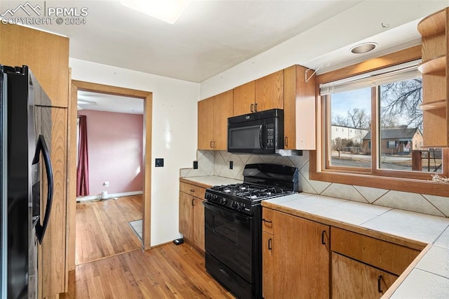 928 Alexander Rd, Colorado Springs, CO 80909 - kitchen featuring black appliances, backsplash, light hardwood / wood-style flooring, and tile countertops