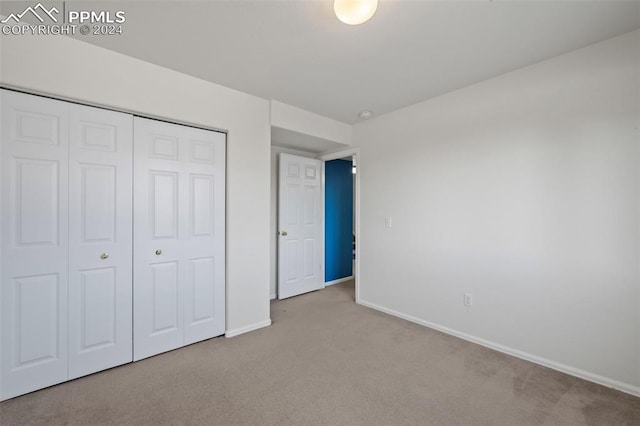 unfurnished bedroom featuring light colored carpet and a closet