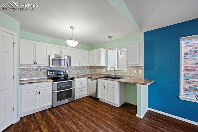 kitchen with appliances with stainless steel finishes, dark hardwood / wood-style flooring, sink, white cabinets, and hanging light fixtures