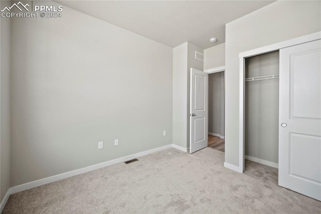 unfurnished bedroom with light carpet and a closet