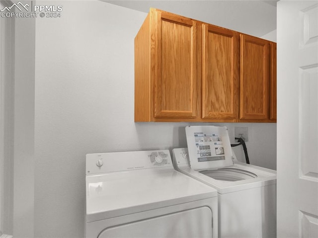 clothes washing area featuring cabinets and separate washer and dryer