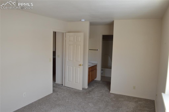 unfurnished bedroom featuring light colored carpet and ensuite bath