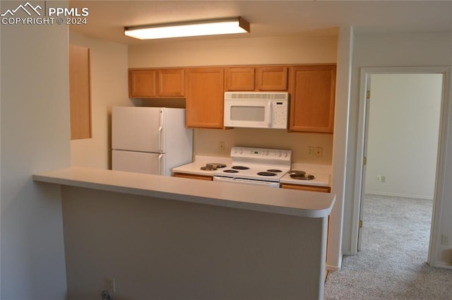 kitchen featuring light colored carpet, white appliances, and kitchen peninsula