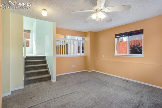 carpeted empty room featuring a textured ceiling, plenty of natural light, and ceiling fan