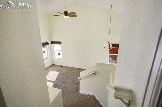 stairs featuring ceiling fan with notable chandelier, carpet floors, and high vaulted ceiling