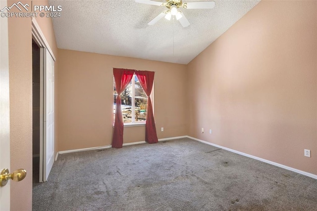 carpeted spare room with lofted ceiling, ceiling fan, and a textured ceiling