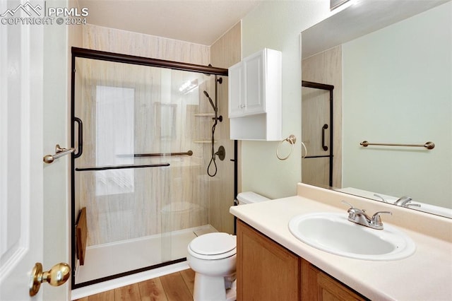 bathroom with hardwood / wood-style floors, vanity, toilet, and walk in shower