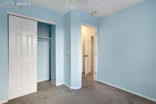 unfurnished bedroom featuring carpet flooring, ceiling fan, a closet, and a textured ceiling