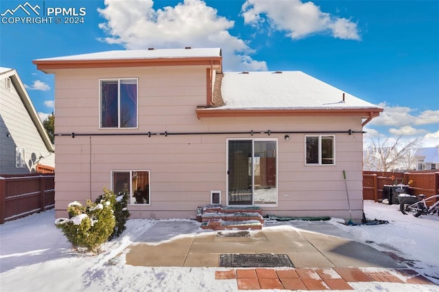 snow covered rear of property featuring a patio area