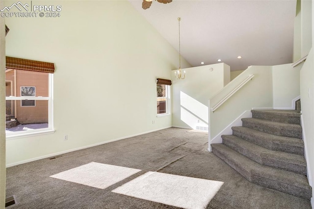 stairs featuring carpet floors, high vaulted ceiling, and ceiling fan with notable chandelier