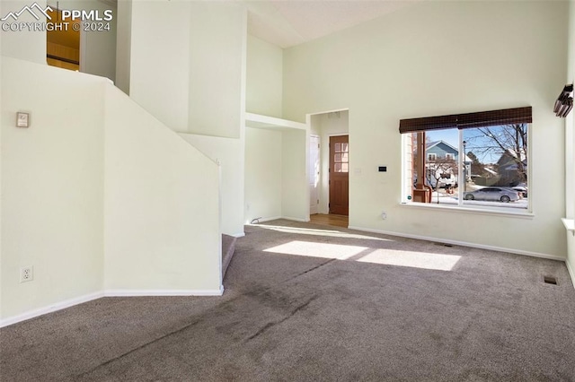 unfurnished living room featuring carpet floors and a high ceiling