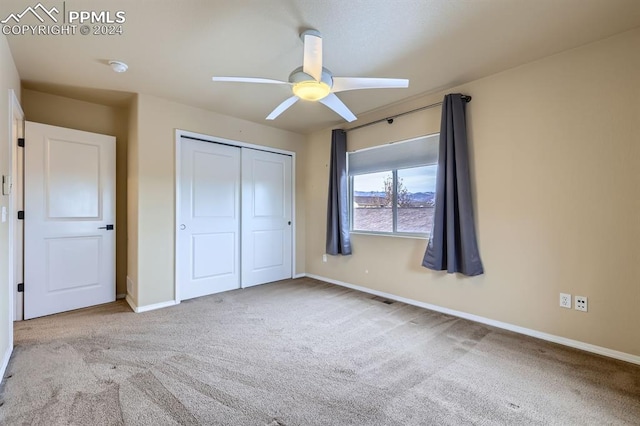 unfurnished bedroom featuring ceiling fan, light carpet, and a closet