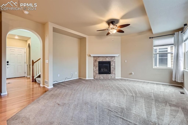 unfurnished living room with a fireplace, carpet flooring, and ceiling fan