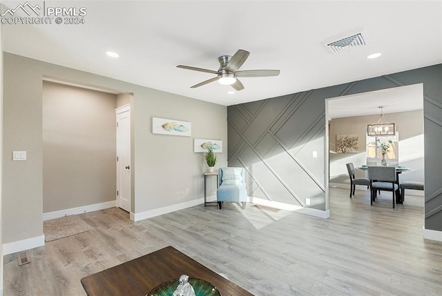 living area featuring ceiling fan with notable chandelier and light wood-type flooring