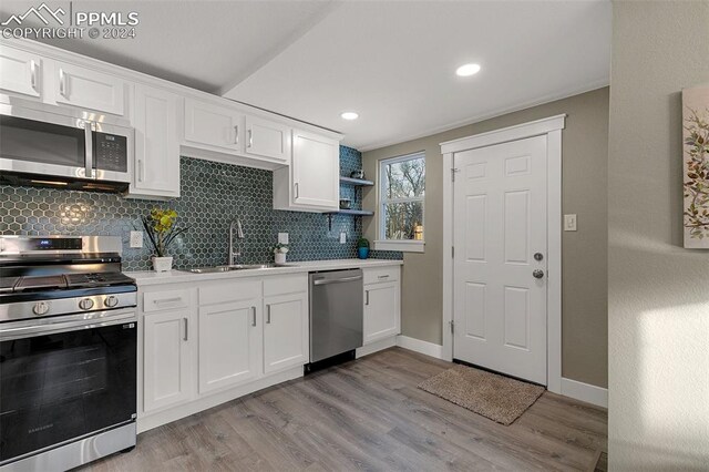 kitchen featuring appliances with stainless steel finishes, light wood-type flooring, white cabinetry, and sink