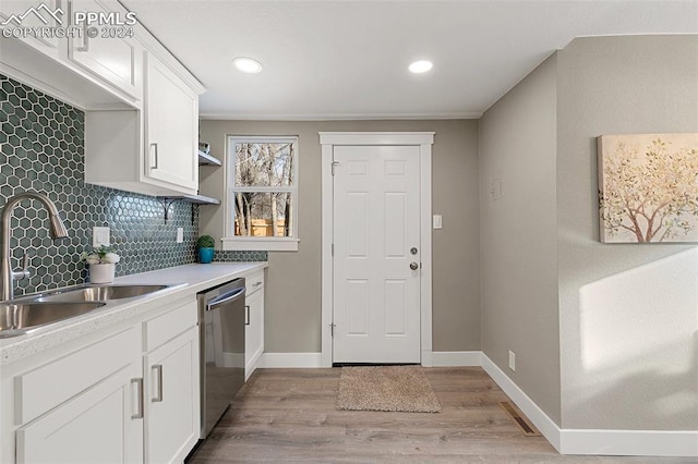 kitchen featuring white cabinets, sink, stainless steel dishwasher, decorative backsplash, and light wood-type flooring