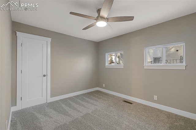 carpeted spare room featuring ceiling fan