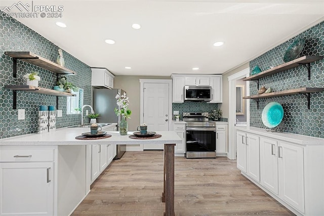 kitchen with sink, decorative backsplash, light hardwood / wood-style floors, white cabinetry, and stainless steel appliances