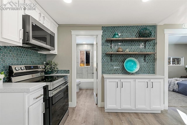 kitchen featuring white cabinets, light wood-type flooring, stainless steel appliances, and tasteful backsplash