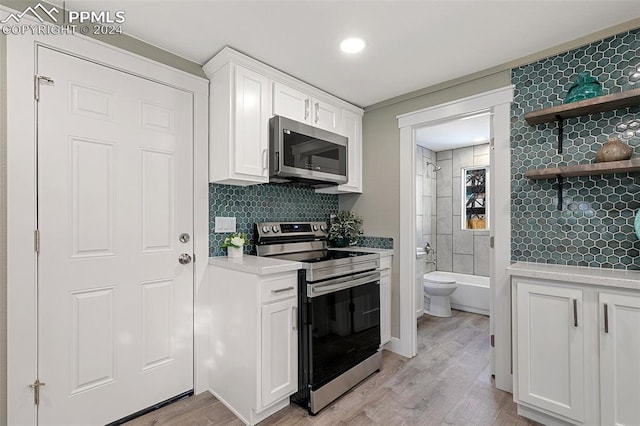 kitchen featuring white cabinets, decorative backsplash, light wood-type flooring, and stainless steel appliances