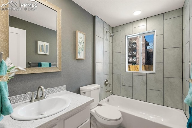 full bathroom featuring vanity, tiled shower / bath combo, and toilet