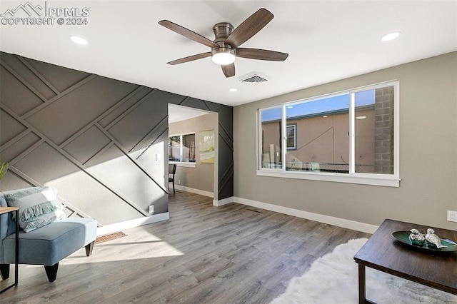 sitting room with ceiling fan and light wood-type flooring