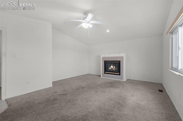 unfurnished living room featuring a tiled fireplace, ceiling fan, carpet floors, and vaulted ceiling