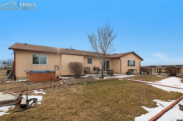 back of property featuring a hot tub, a patio area, and a lawn