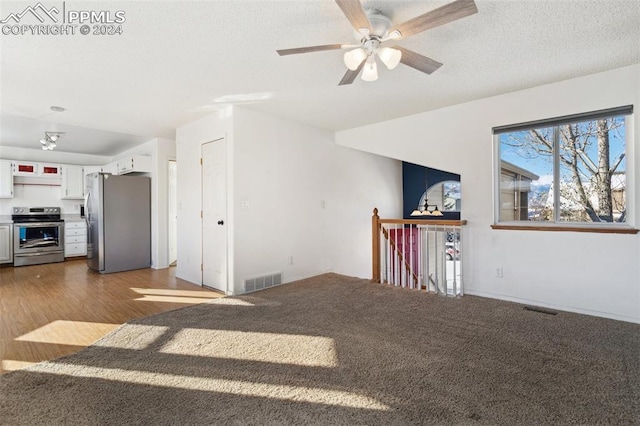 unfurnished living room with ceiling fan, dark hardwood / wood-style flooring, and a textured ceiling