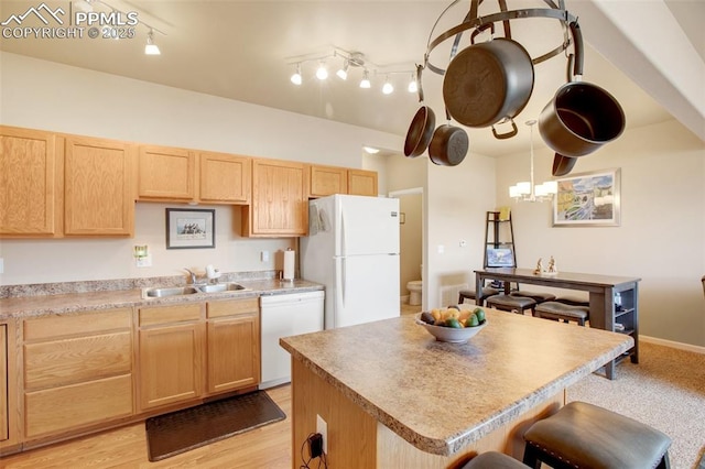 kitchen featuring white appliances, hanging light fixtures, light brown cabinetry, a kitchen island, and sink