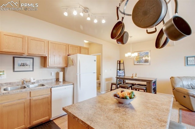 kitchen with white appliances, hanging light fixtures, light brown cabinetry, sink, and an inviting chandelier