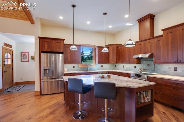 kitchen with light stone countertops, sink, a center island, pendant lighting, and appliances with stainless steel finishes