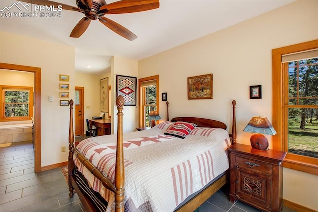 bedroom featuring dark tile patterned flooring, ceiling fan, ensuite bath, and multiple windows