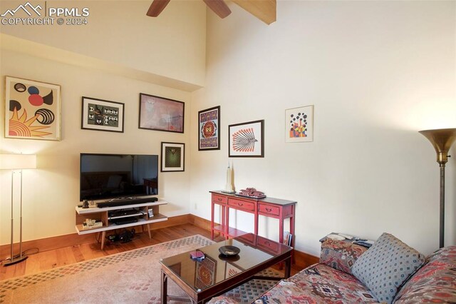 living room featuring hardwood / wood-style flooring, ceiling fan, and a high ceiling