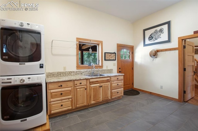 washroom featuring dark tile patterned flooring, cabinets, sink, and stacked washer and clothes dryer