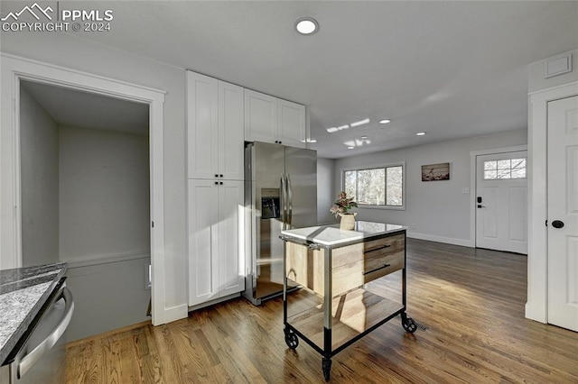 kitchen featuring stone counters, white cabinets, stainless steel appliances, and wood-type flooring