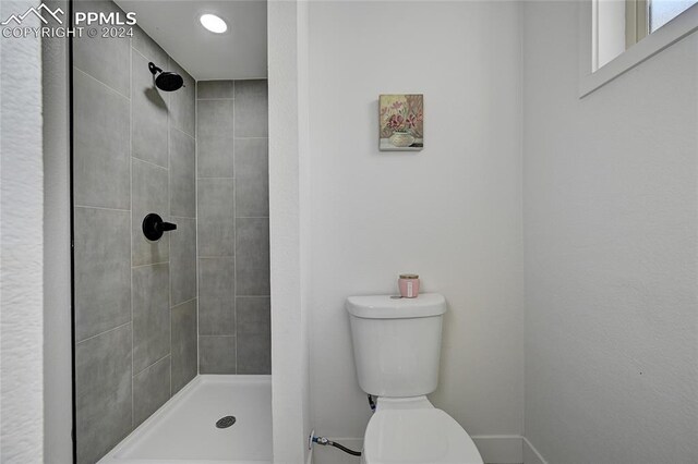 bathroom featuring a tile shower and toilet